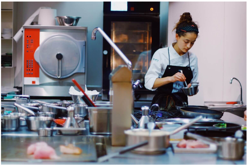 Chef preparing food at a stainless-steel workstation in a commercial kitchen